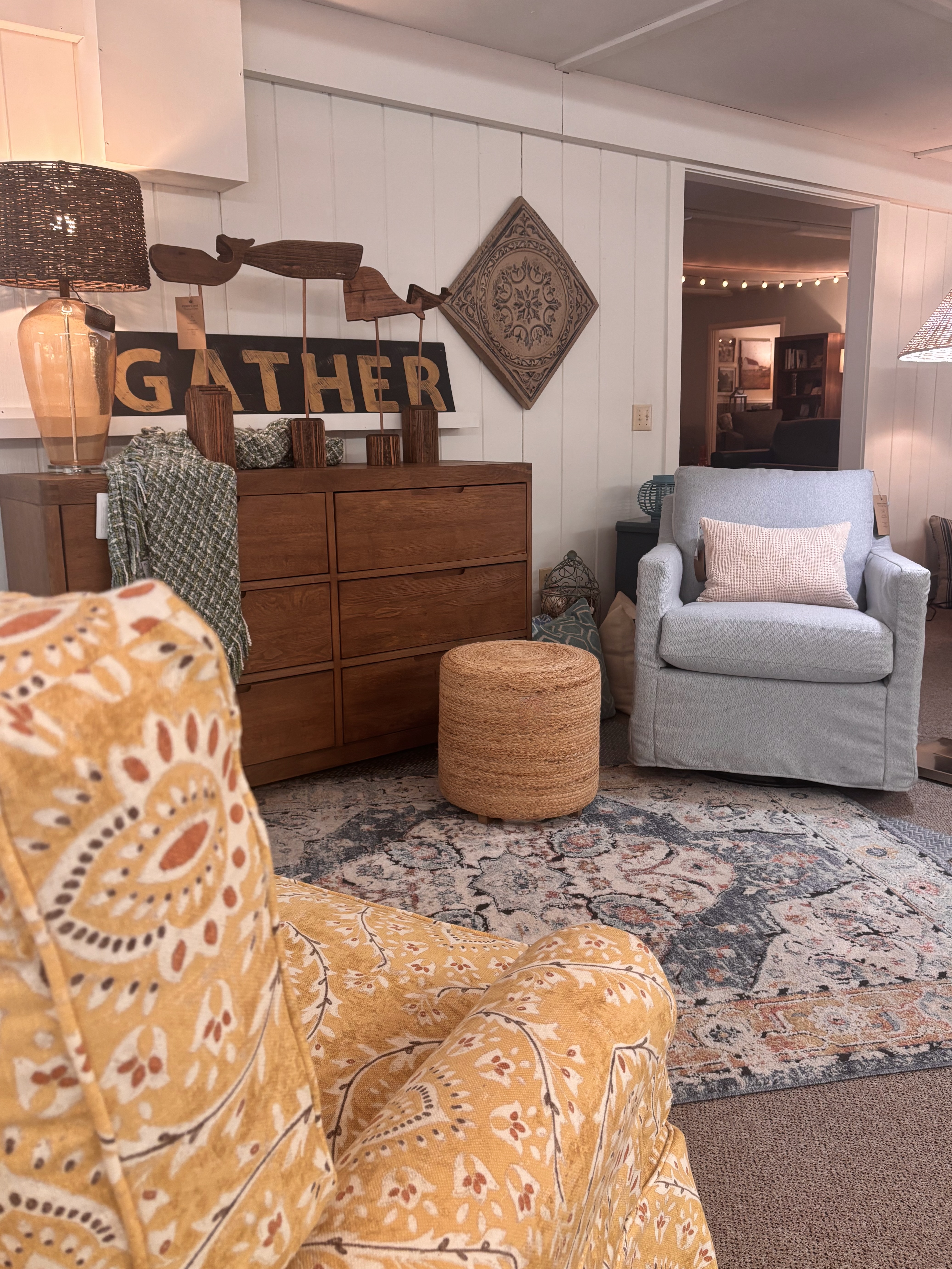 Perry's Home Furnishings & Design showroom with a "gather" sign above a dresser with two chairs, one in a yellow floral pattern