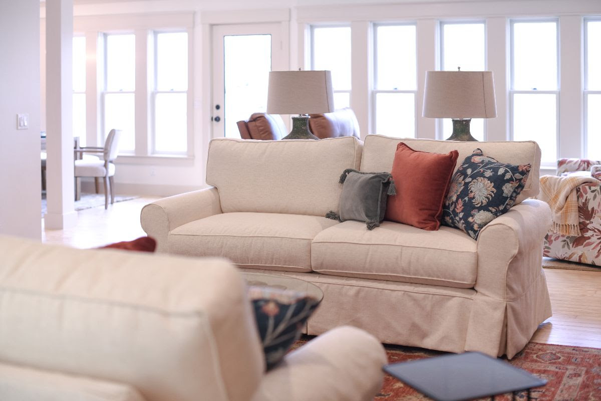 Livingroom with sightline into dining area. Beautiful throw pillows with a floral pattern on sofa and lamps on the sofa table. Interior design by Perry's Home Furnishings & Design.